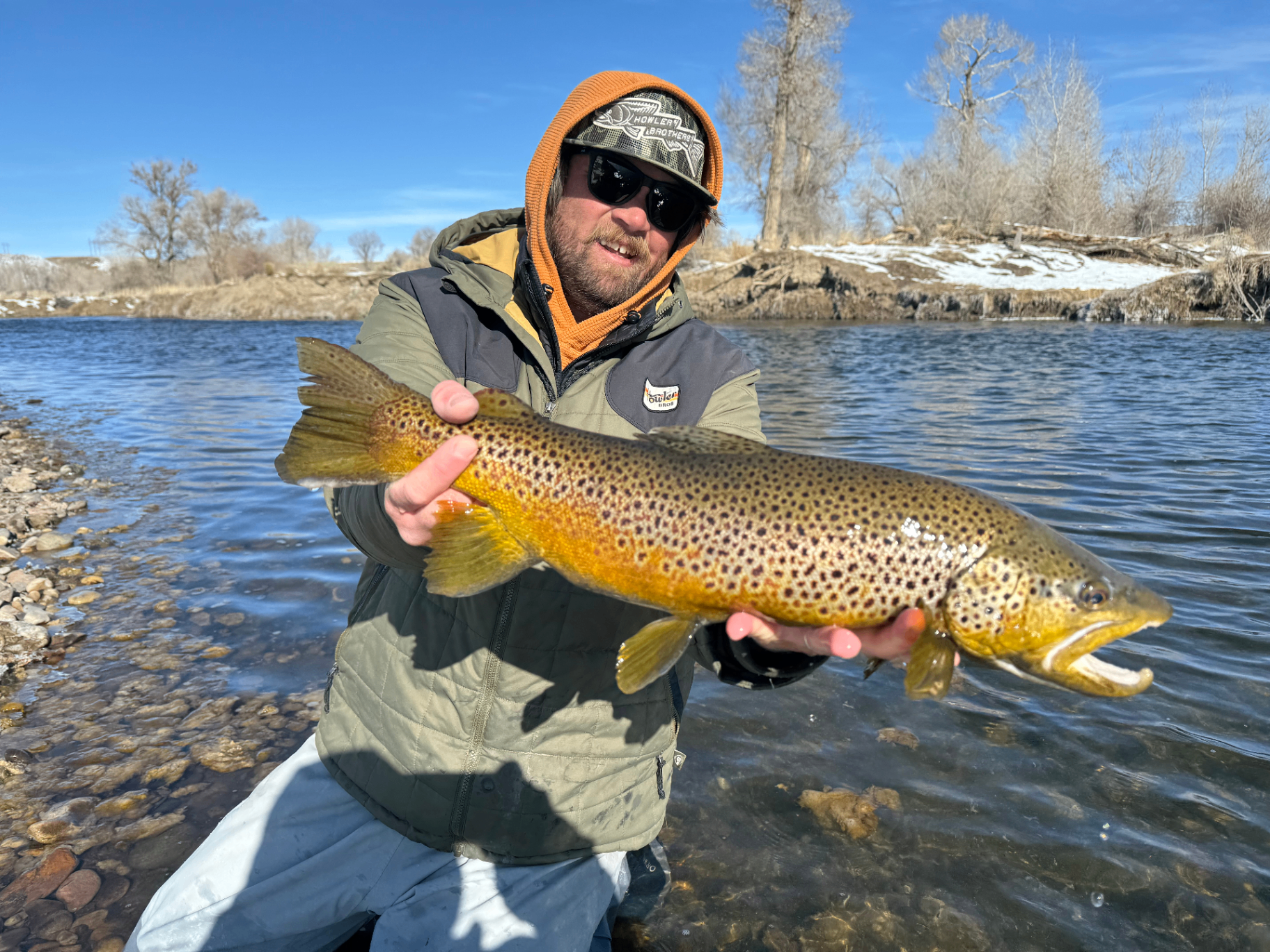 Chris Chastain holding a trophy brown trout on a rocky Utah river